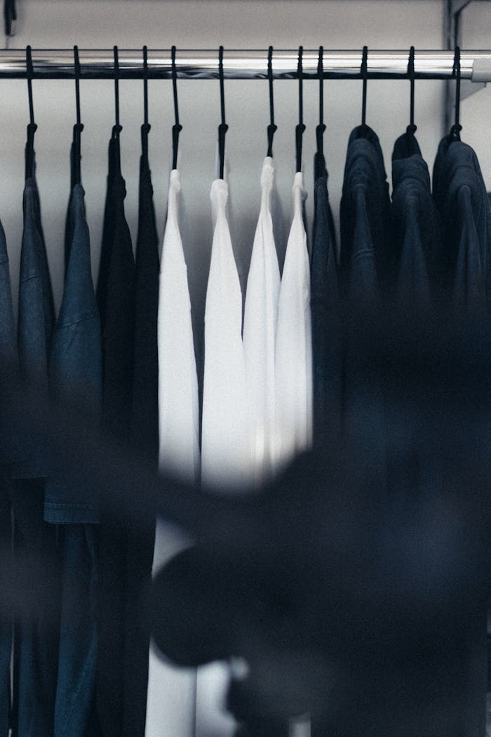 Stylish black and white clothing neatly arranged on hangers in a minimal wardrobe.